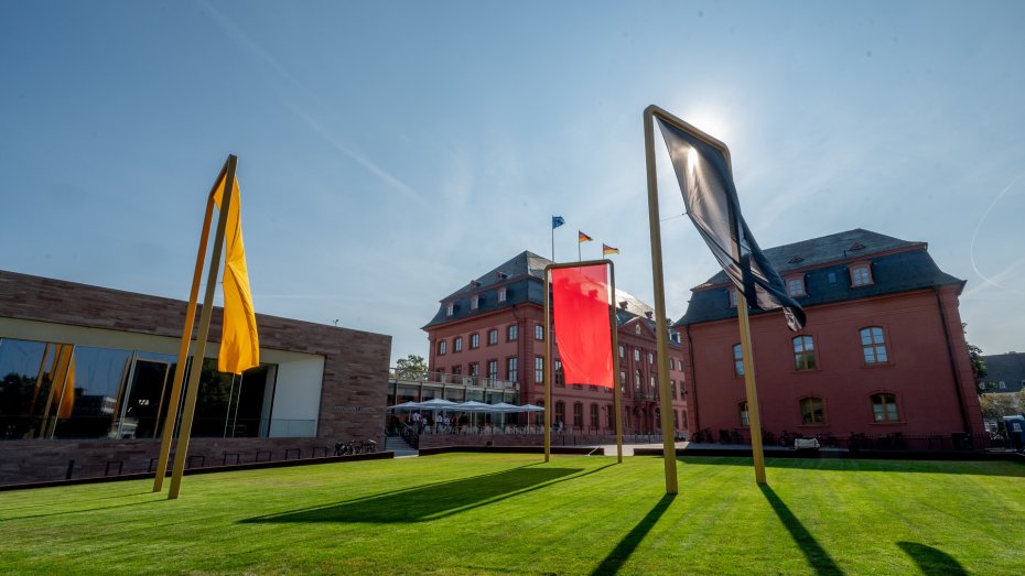 Der Landtag Rheinland-Pfalz von außen mit Flaggenkunstwerk davor