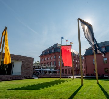 Der Landtag Rheinland-Pfalz von außen mit Flaggenkunstwerk davor